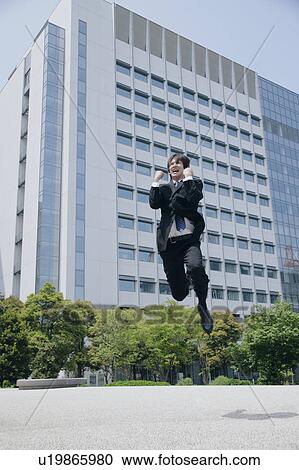 Stock Image - A young man in suit jumping. Fotosearch