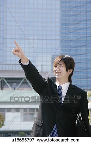 Stock Photo - A young man in suit pointing ahead. Fotosearch