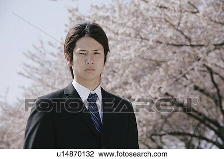 A young man in suit standing in front of cherry blossoms View Large Photo Image Stock Image - A young man in suit standing in front of cherry blossoms. Fotosearch