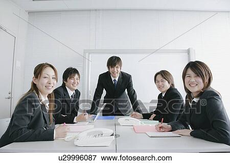 Stock Photo - Five young businessperson sitting in meeting room. Fotosearch