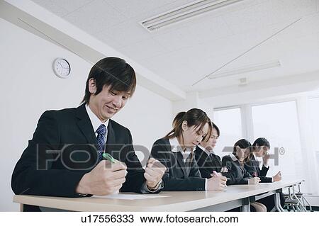 Stock Image - Five young people writing on exam paper. Fotosearch