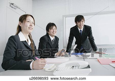 Stock Image - Three young businessperson sitting in meeting room. Fotosearch