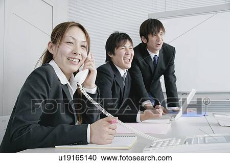 Stock Image - Three young businessperson working in office. Fotosearch