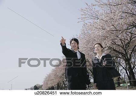 Young man in suit pointing ahead and a young woman standing aside View Large Photo Image Stock Image - Young man in suit pointing ahead and a young woman standing aside. Fotosearch