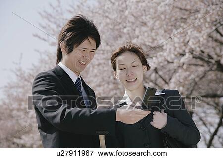 Young woman and man in suit looking at mobile phone View Large Photo Image Stock Photo - Young woman and man in suit looking at mobile phone. Fotosearch