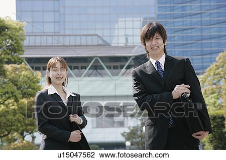 Stock Image - Young woman and man in suit smiling. Fotosearch