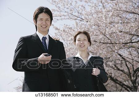 Stock Image - Young woman and man in suit standing. Fotosearch