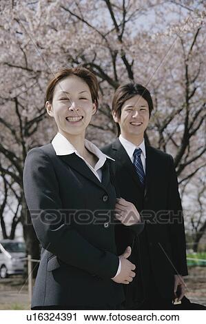 Stock Image - Young woman and man in suit standing. Fotosearch