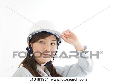 Picture - A female construction worker wearing a hardhat. Fotosearch