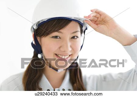 Stock Image - A female construction worker wearing a hardhat. Fotosearch