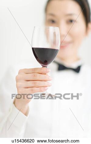 Stock Image - A female sommelier holding a glass of wine. Fotosearch