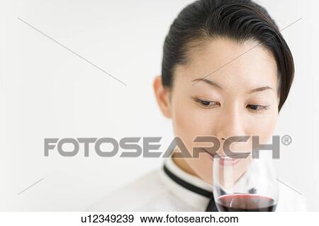 Stock Photo - A female sommelier sniffing a glass of wine. Fotosearch