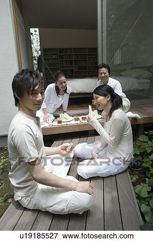 Stock Photo - A family with adult children having lunch in porch. Fotosearch