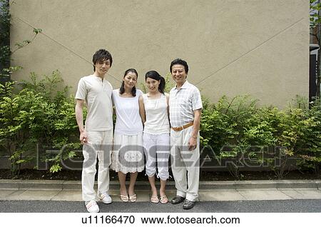 Stock Image - A family with adult children standing in front of house. Fotosearch