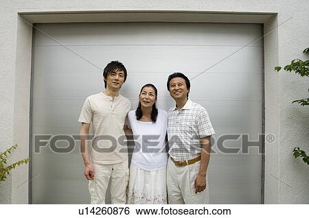 Stock Photograph - A family with adult son standing in front of garage. Fotosearch