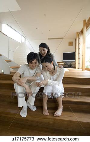 Stock Image - Brother and sister looking at mobile phone. Fotosearch
