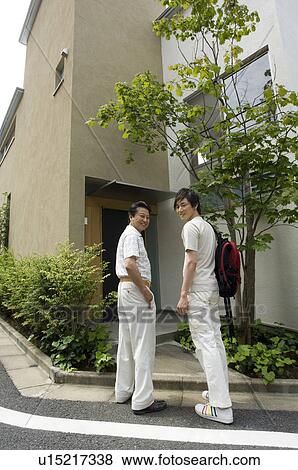Father and son standing in front of house View Large Photo Image Stock Photo - Father and son standing in front of house. Fotosearch