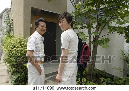 Father and son standing in front of house View Large Photo Image Stock Photograph - Father and son standing in front of house. Fotosearch