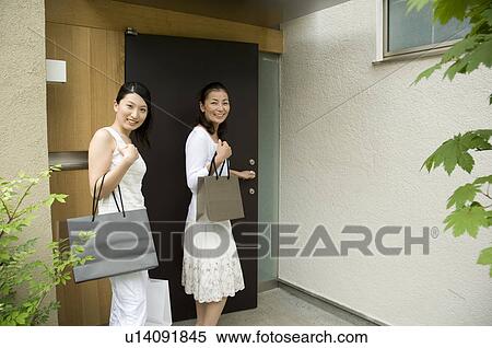 Stock Photography - Mother and daughter coming home from shopping. Fotosearch