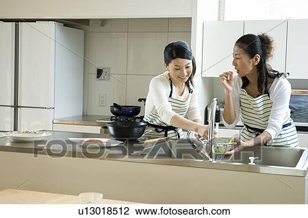Stock Image - Mother and daughter cooking in kitchen. Fotosearch