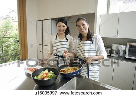 Stock Photo - Mother and daughter cooking in kitchen. Fotosearch