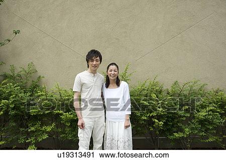 Stock Image - Mother and son standing in front of house. Fotosearch