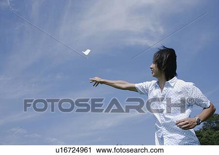Stock Image - A young man flying paper airplane. Fotosearch