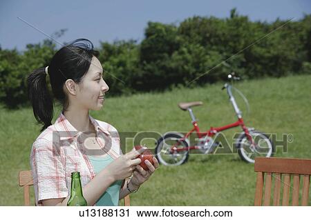 Stock Image - A young woman peeling an apple outside. Fotosearch