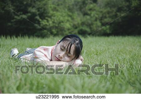 Stock Photography - A young woman sleeping on grass field. Fotosearch
