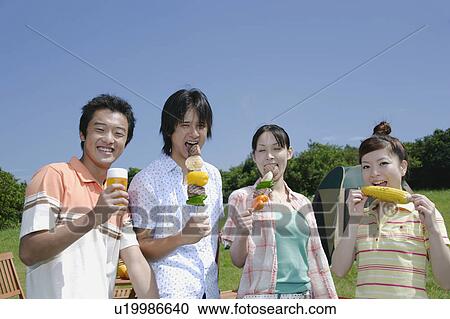 Stock Image - Four young people eating barbecue. Fotosearch