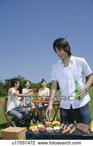 Stock Image - Four young people enjoying barbecue. Fotosearch