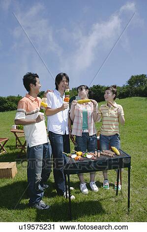 Stock Image - Four young people enjoying barbecue. Fotosearch