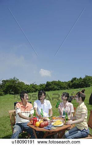 Stock Image - Four young people enjoying picnic. Fotosearch