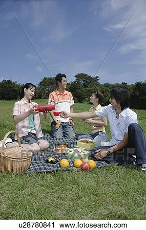 Stock Image - Four young people enjoying picnic. Fotosearch