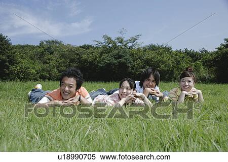 Four young people lying on grass View Large Photo Image Stock Photography - Four young people lying on grass. Fotosearch