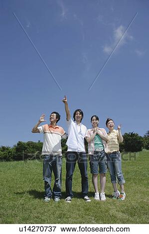 Stock Photo - Four young people pointing directions. Fotosearch