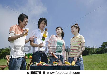 Stock Photography - Four young people preparing barbecue. Fotosearch