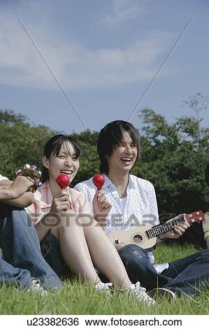 Stock Photograph - Four young people singing on grass field. Fotosearch