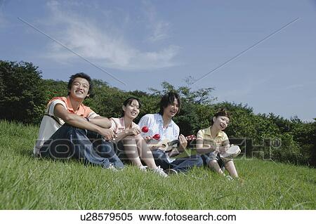 Stock Photography - Four young people singing on grass field. Fotosearch
