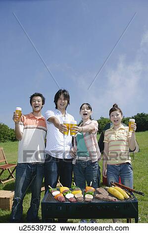 Stock Image - Four young people toasting with beer. Fotosearch