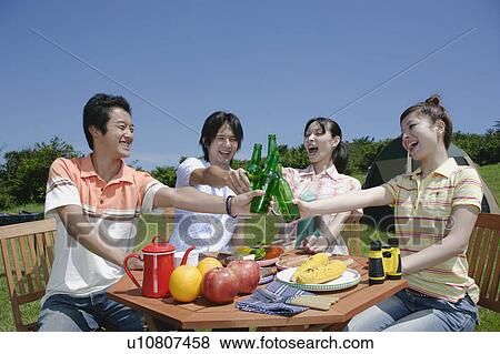 Stock Photo - Four young people toasting with beer. Fotosearch