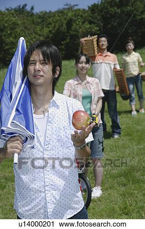 Stock Image - Four young people walking with picnic baskets. Fotosearch