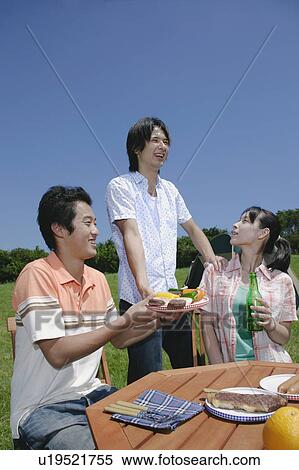 Stock Photography - Three young people enjoying picnic. Fotosearch