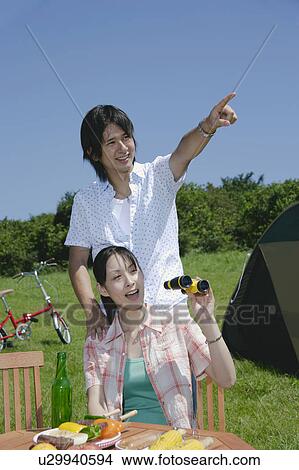 Picture - Young couple looking ahead with binoculars. Fotosearch