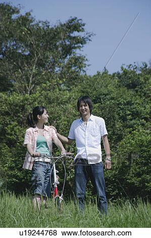 Stock Photo - Young couple walking with bicycle. Fotosearch