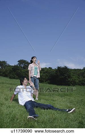 Stock Image - Young couple yelling on grass field. Fotosearch