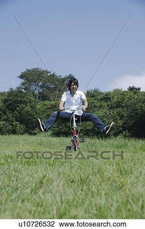 Young man riding on bicycle View Large Photo Image Stock Image - Young man riding on bicycle. Fotosearch