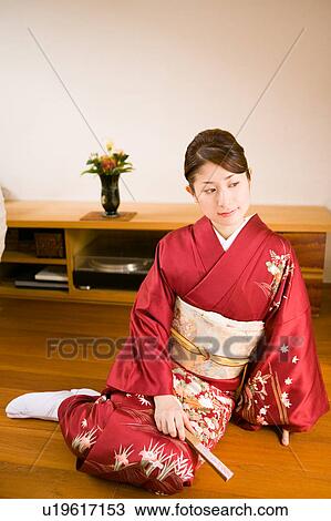 Stock Image - A young woman wearing kimono sitting on floor. Fotosearch