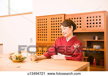 Stock Image - A young woman wearing kimono sitting. Fotosearch