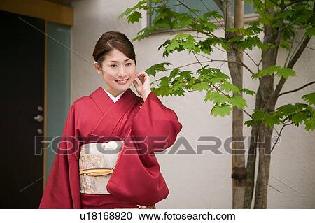 A young woman wearing kimono standing in front of door View Large Photo Image Stock Image - A young woman wearing kimono standing in front of door. Fotosearch